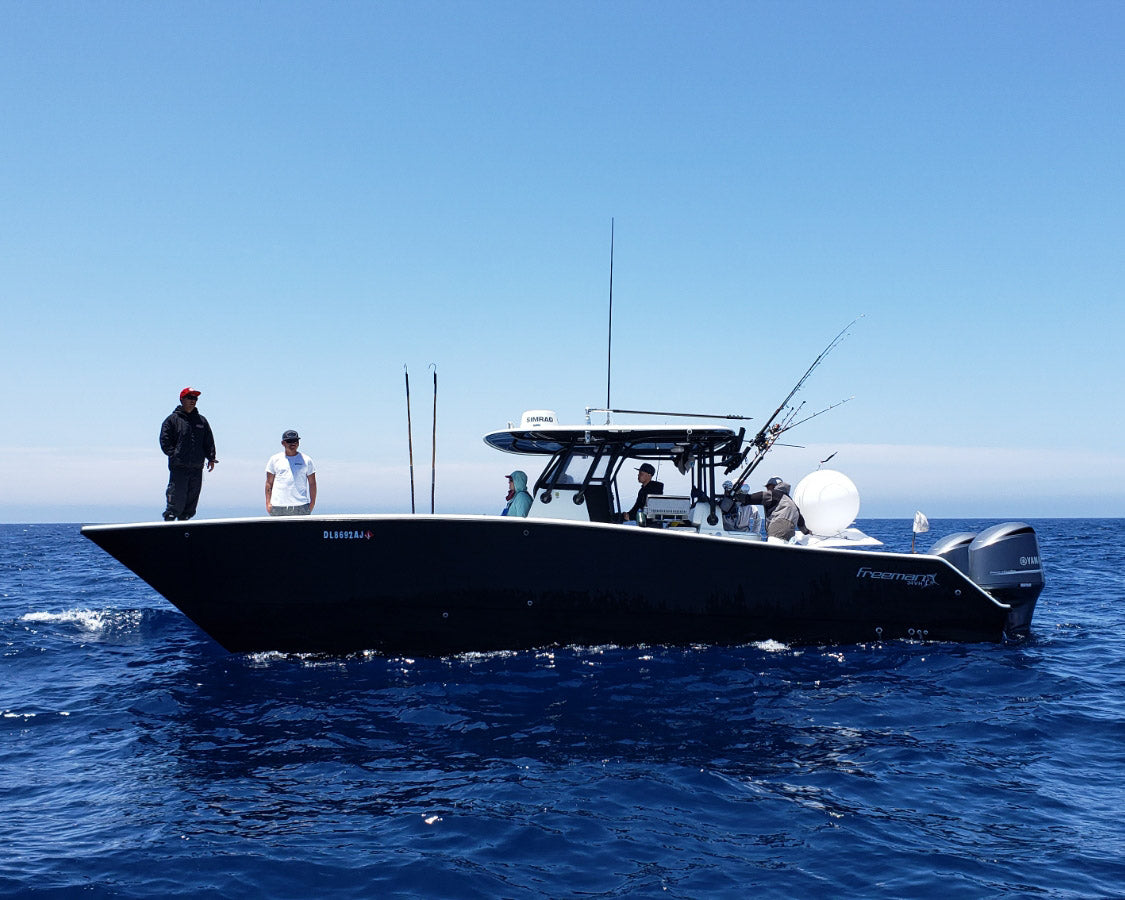 Anglers wearing Ahcor Offshore performance apparel kite fishing with a helium balloon setup on a Freeman boat